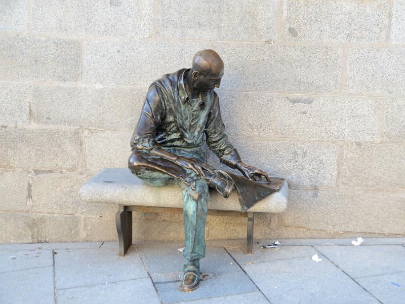 spain0036.jpg - A metal sculpture of a man reading a newspaper on a bench 
